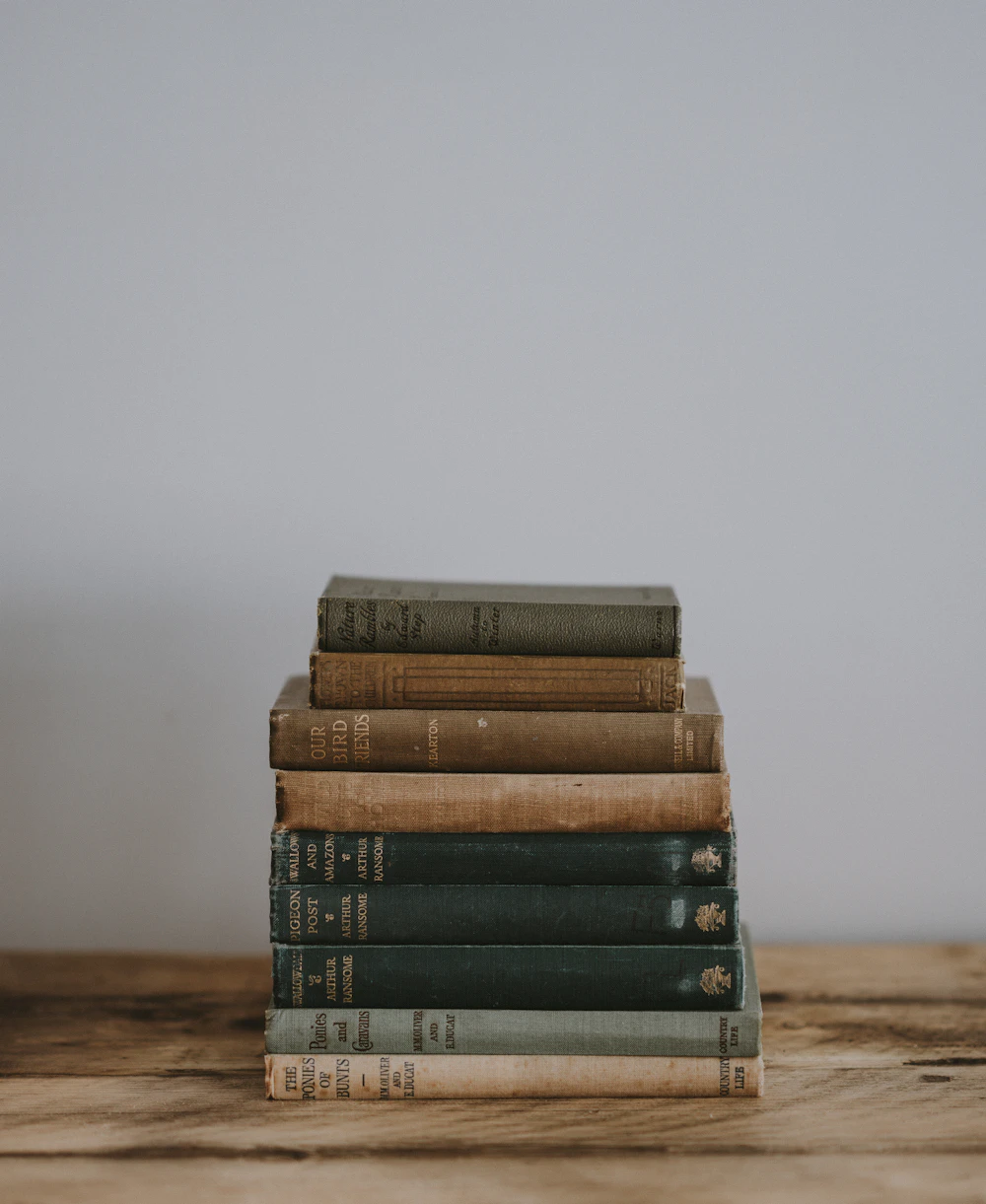 Stack of well-read vintage books on a wooden table