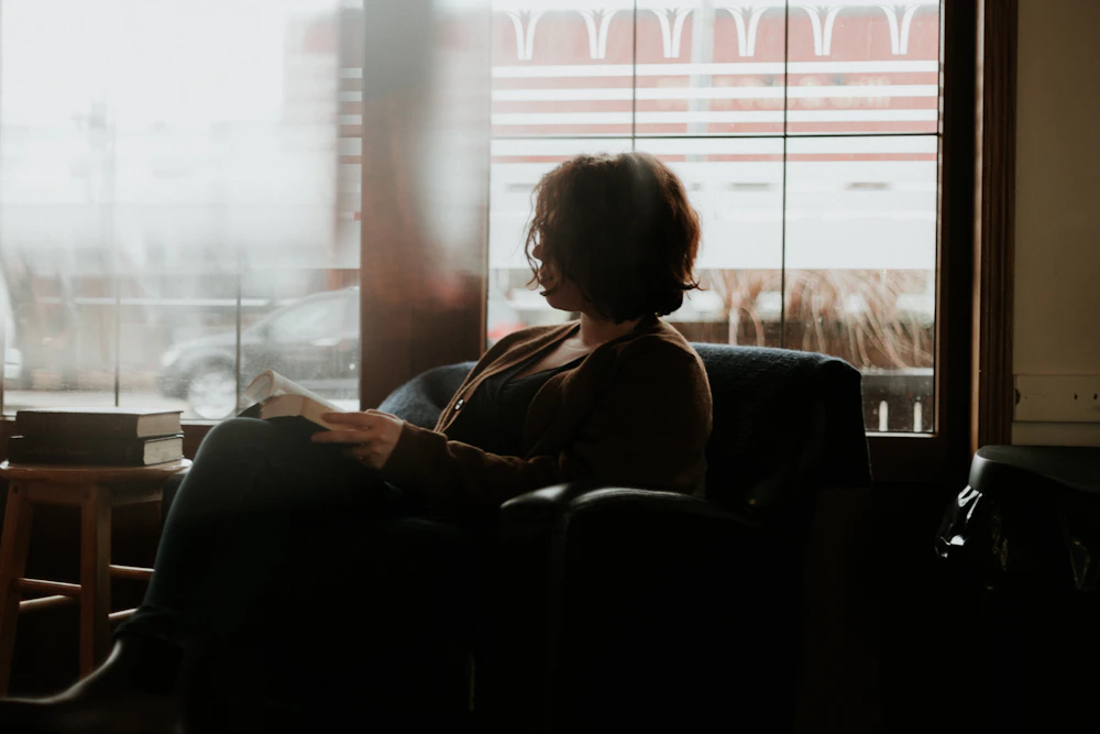 Woman reading alone in a warm, quiet room, deep in thought
